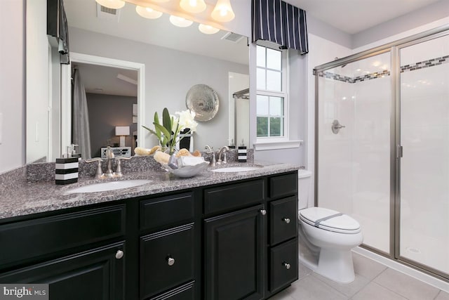 bathroom with tile patterned floors, vanity, a shower with shower door, and toilet