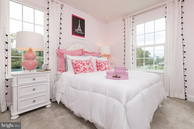 bedroom with multiple windows and light colored carpet