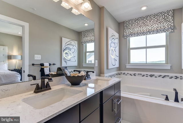 bathroom featuring vanity, a wealth of natural light, and tiled bath