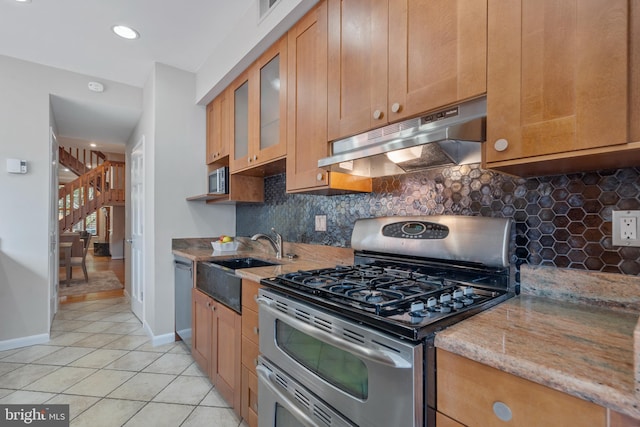 kitchen with appliances with stainless steel finishes, backsplash, light stone counters, sink, and light tile patterned floors