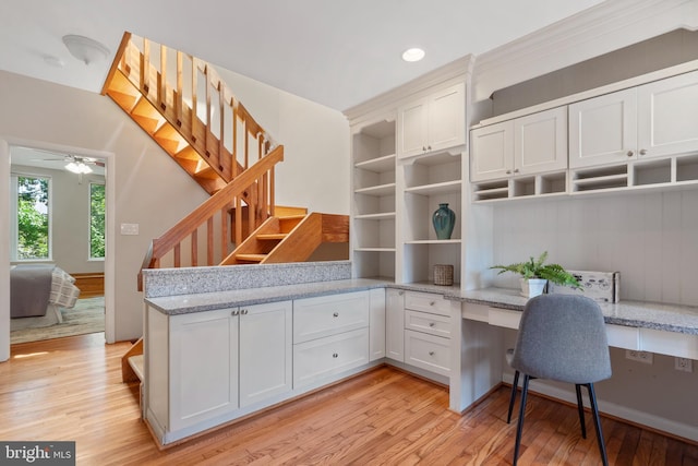 home office featuring ceiling fan, light wood-type flooring, and built in desk