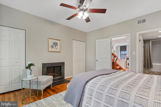 bedroom featuring ceiling fan, wood-type flooring, and two closets