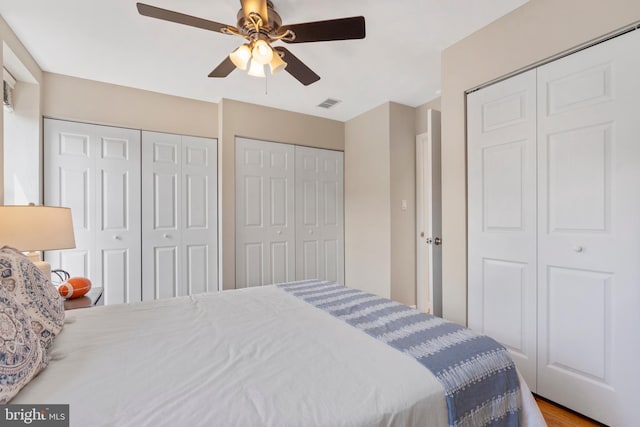 bedroom with multiple closets, ceiling fan, and wood-type flooring