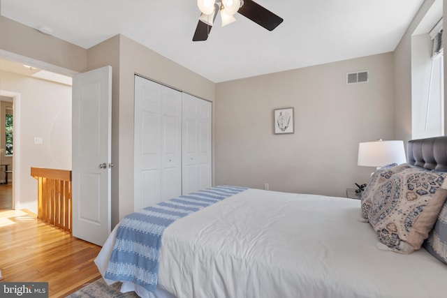 bedroom with ceiling fan, wood-type flooring, and a closet