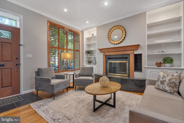 living room featuring built in shelves, crown molding, hardwood / wood-style flooring, and a wealth of natural light