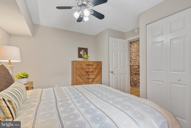 bedroom with ceiling fan, brick wall, and a closet