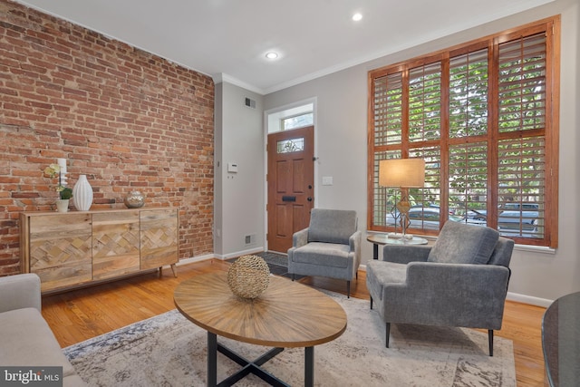 living area with hardwood / wood-style flooring, crown molding, and brick wall