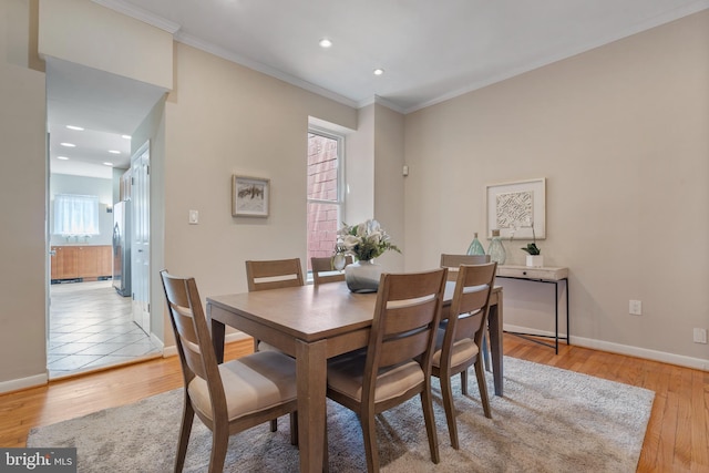 dining area with light hardwood / wood-style flooring and ornamental molding