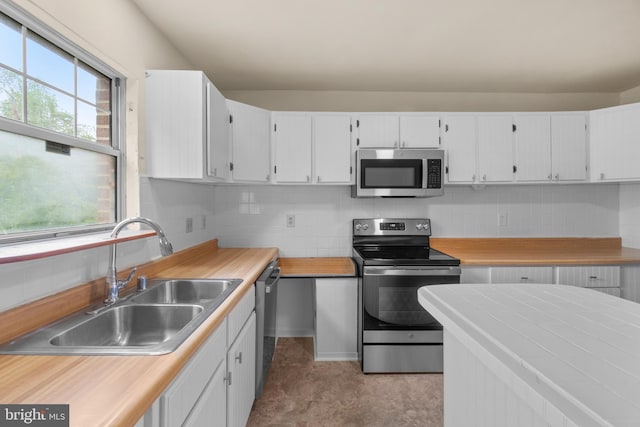 kitchen with tasteful backsplash, sink, white cabinets, and appliances with stainless steel finishes