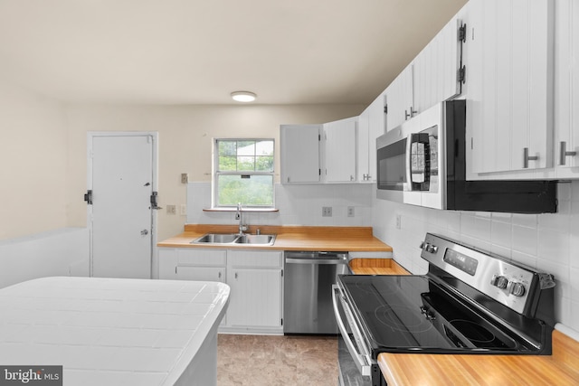 kitchen featuring appliances with stainless steel finishes, tasteful backsplash, white cabinetry, and sink