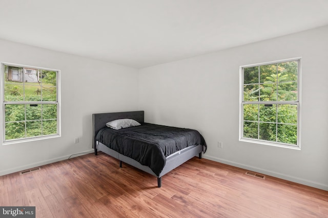 bedroom with hardwood / wood-style flooring and multiple windows