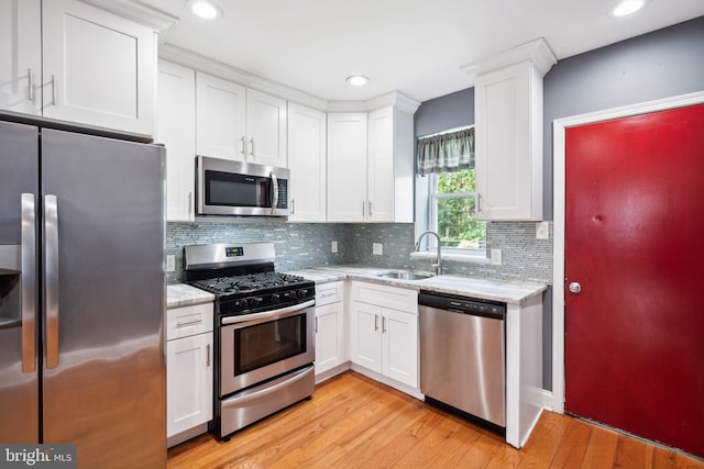 kitchen with white cabinetry, sink, light stone counters, and appliances with stainless steel finishes