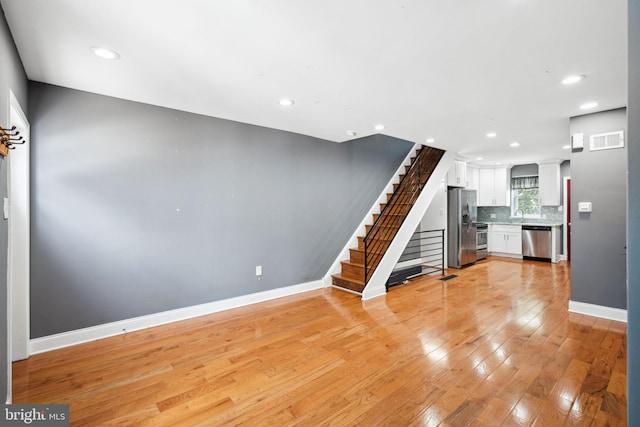 unfurnished living room featuring sink and light wood-type flooring