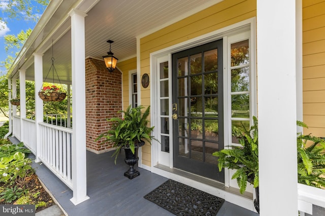 entrance to property featuring covered porch and brick siding