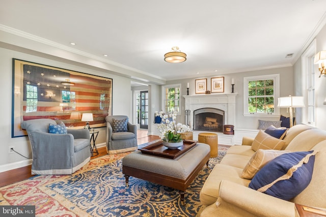 living area featuring visible vents, wood finished floors, a fireplace, crown molding, and baseboards