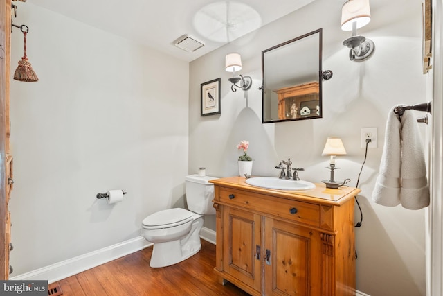 bathroom with visible vents, baseboards, toilet, wood finished floors, and vanity