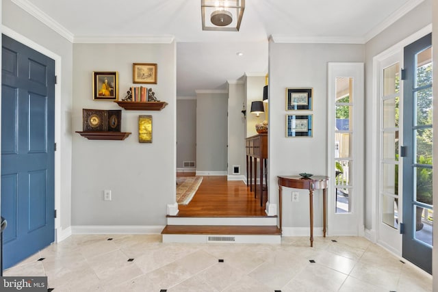 tiled entryway with visible vents, crown molding, and baseboards