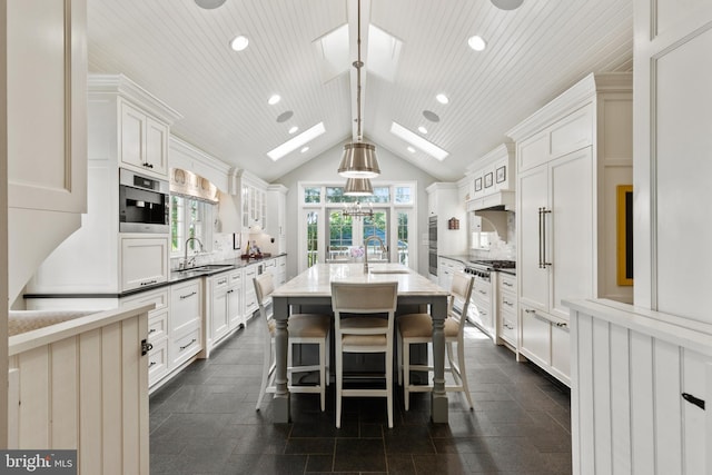 kitchen featuring a sink, stainless steel appliances, vaulted ceiling with skylight, and decorative backsplash