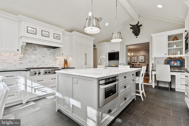 kitchen featuring beam ceiling, decorative backsplash, white cabinets, stainless steel appliances, and a kitchen island with sink