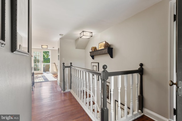 hall with an upstairs landing, dark wood-style floors, and baseboards