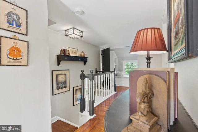 hallway featuring an upstairs landing, baseboards, and wood finished floors