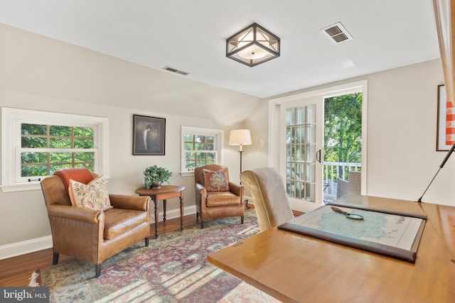 office space with vaulted ceiling, wood finished floors, visible vents, and baseboards