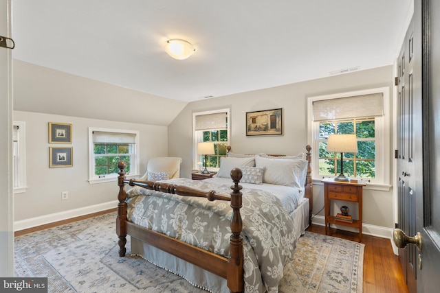 bedroom with visible vents, baseboards, wood finished floors, and vaulted ceiling