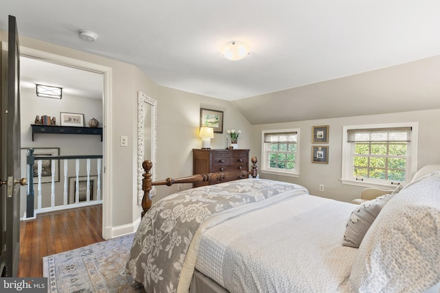 bedroom with baseboards, wood-type flooring, and lofted ceiling