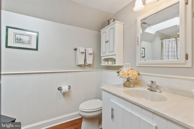 full bathroom featuring vanity, toilet, wood finished floors, and wainscoting