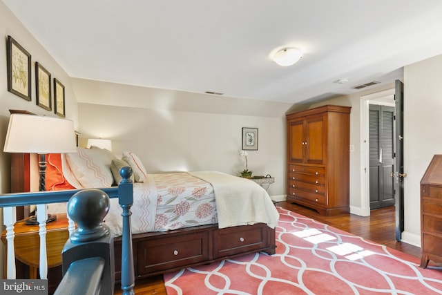 bedroom featuring lofted ceiling, wood finished floors, visible vents, and baseboards