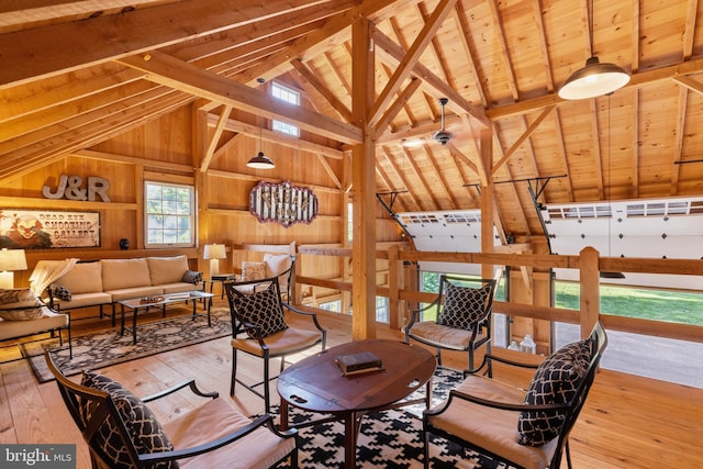 living area featuring wooden walls, wood ceiling, beam ceiling, hardwood / wood-style flooring, and high vaulted ceiling