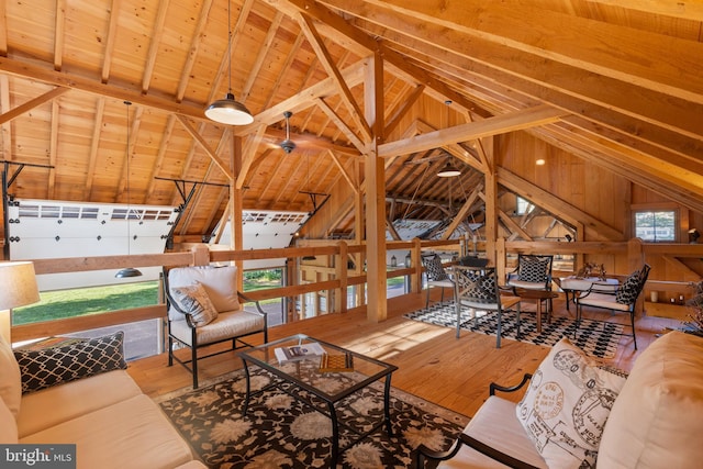 living area featuring wood-type flooring, wood walls, and vaulted ceiling with beams