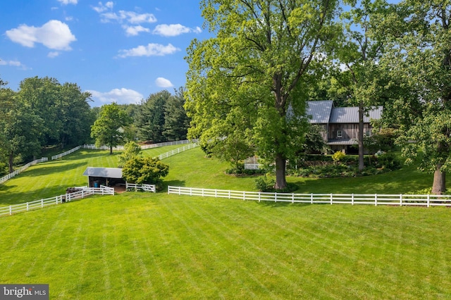 view of yard featuring an outdoor structure, a rural view, and fence