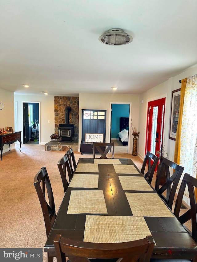 dining area featuring light colored carpet, a wood stove, and billiards