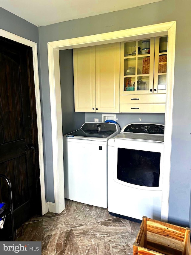 clothes washing area featuring cabinets and washer and clothes dryer