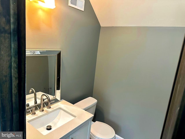 bathroom with vanity, toilet, and vaulted ceiling