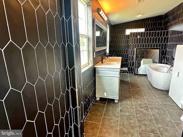 bathroom with tile patterned floors, plenty of natural light, sink, and tile walls