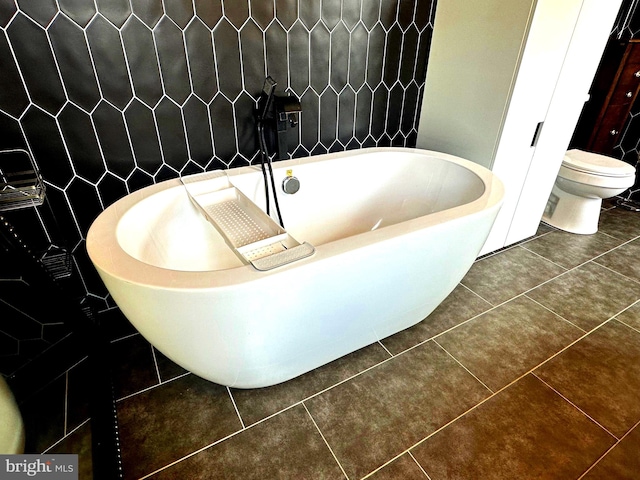 bathroom with tile patterned flooring, toilet, a bath, and tile walls