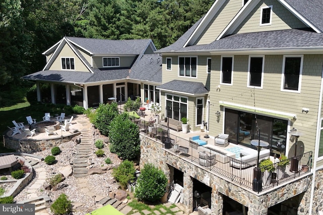 rear view of property featuring an outdoor living space with a fire pit and a patio