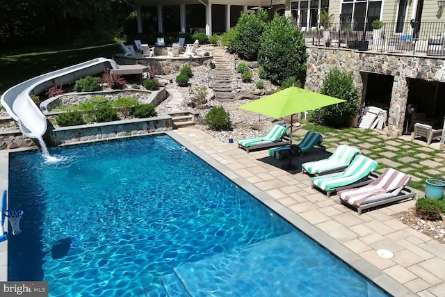 view of pool featuring an outdoor stone fireplace, a patio, and a water slide