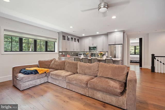 living room featuring ceiling fan, a healthy amount of sunlight, and light wood-type flooring