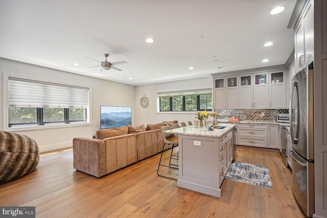 kitchen featuring a kitchen breakfast bar, light hardwood / wood-style flooring, light stone counters, and a kitchen island with sink