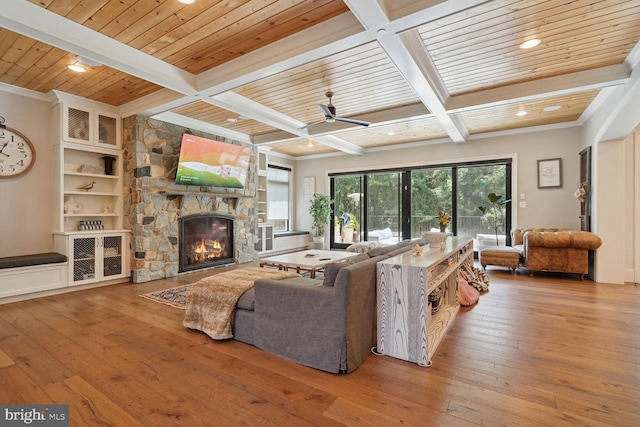 living room featuring coffered ceiling, light hardwood / wood-style flooring, ceiling fan, built in features, and a fireplace