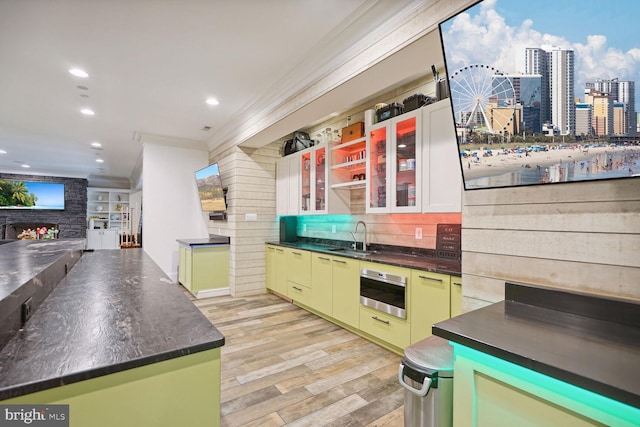 kitchen with oven, sink, crown molding, green cabinetry, and a fireplace