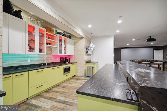 kitchen featuring decorative backsplash, wall oven, crown molding, and sink