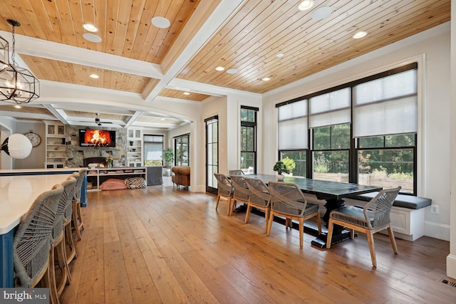 dining space with hardwood / wood-style flooring, built in features, a fireplace, beamed ceiling, and wood ceiling