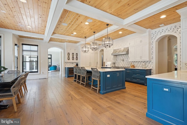 kitchen featuring pendant lighting, wooden ceiling, white cabinets, blue cabinets, and custom range hood