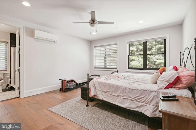 bedroom with a wall unit AC, ceiling fan, and light hardwood / wood-style flooring