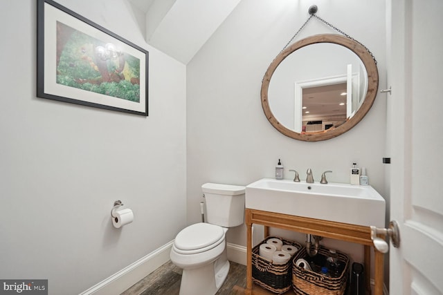 bathroom featuring sink, toilet, lofted ceiling, and hardwood / wood-style flooring