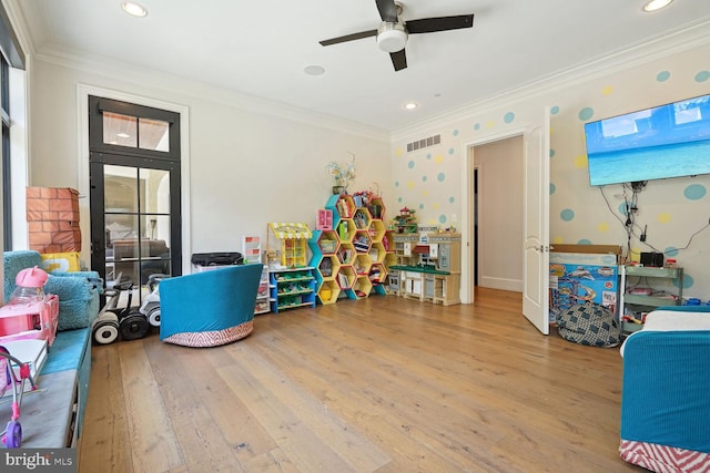 playroom with ceiling fan, light wood-type flooring, and ornamental molding